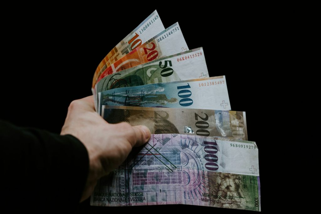 Hand holding Swiss francs of various denominations