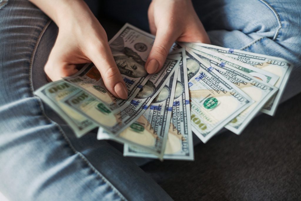 Person holding multiple one-hundred-dollar bills