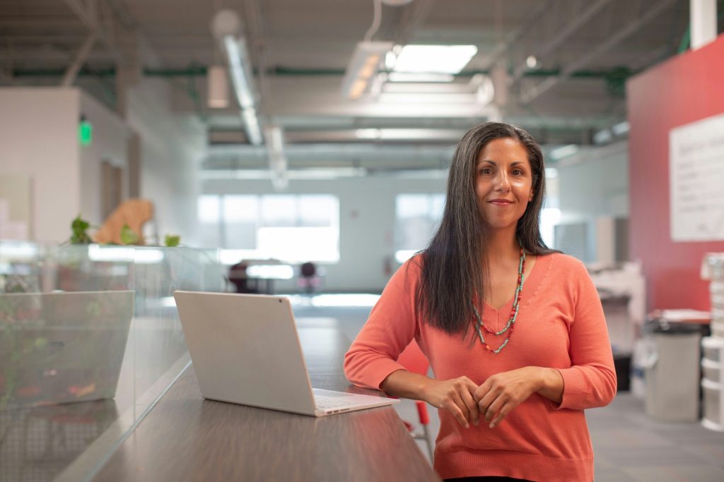 Woman in office smiling, laptop nearby